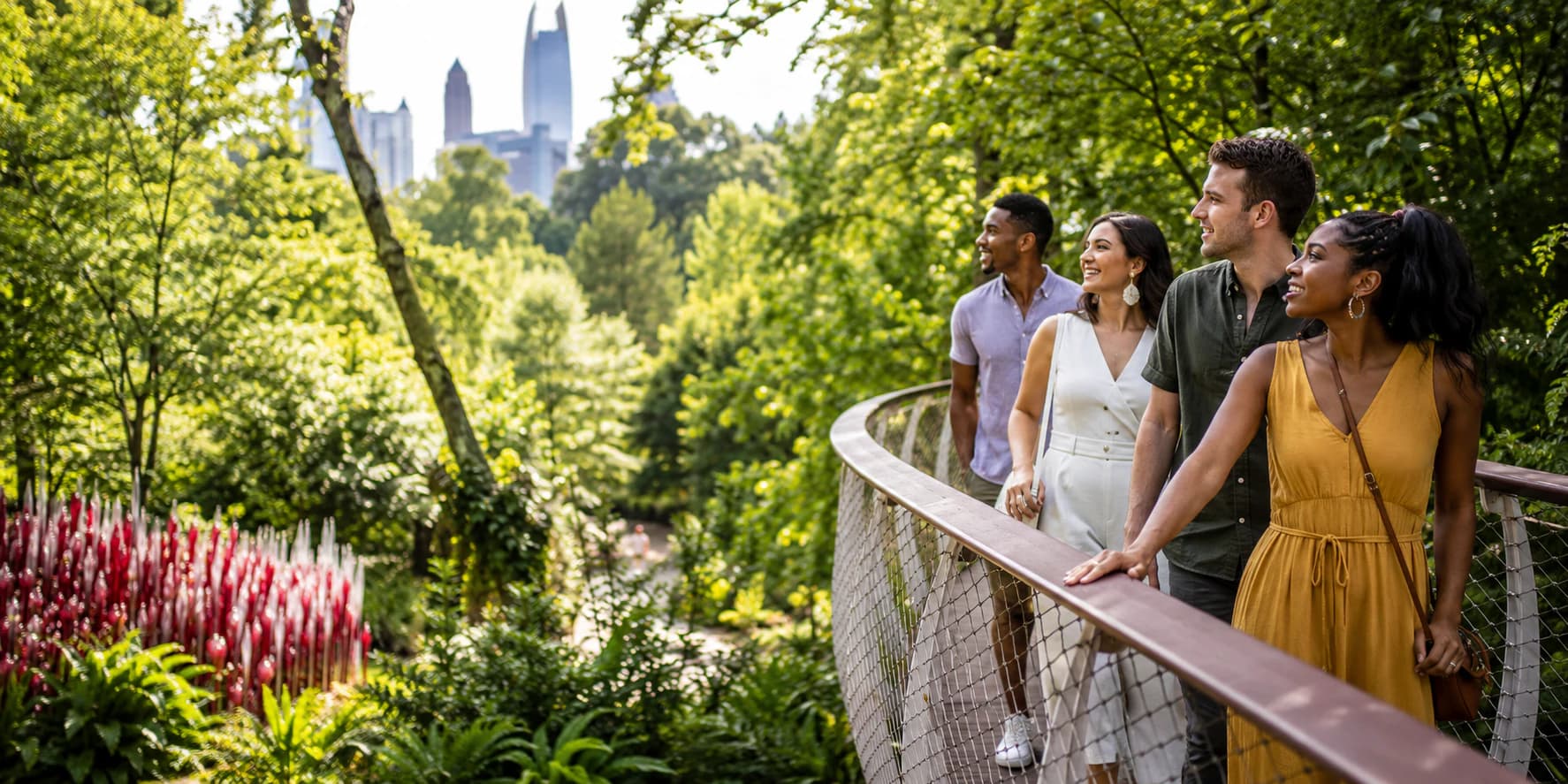 Friends enjoying a lush garden canopy walk with Atlanta's skyline beyond